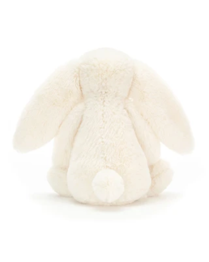 An off-white plush bunny toy shown from the back, featuring long floppy ears and a small round tail, photographed against a seamless white background.