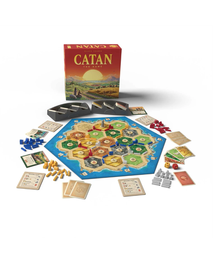 Catan board game set displayed on a white background, including the red game box, blue hexagonal board, play cards, tokens, and other game components arranged around it.
