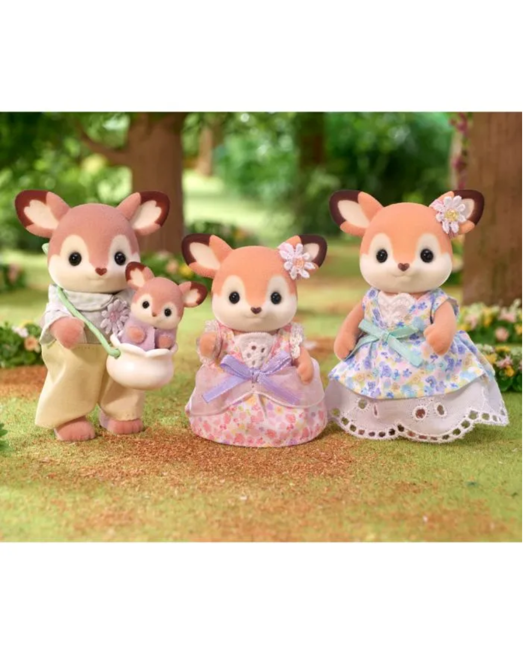 Three sylvanian deer stand on a grassy surface in a garden setting. The left figure holds a small white pot, the center figure wears a pink and lavender dress, and the right figure wears a blue and lavender floral dress.