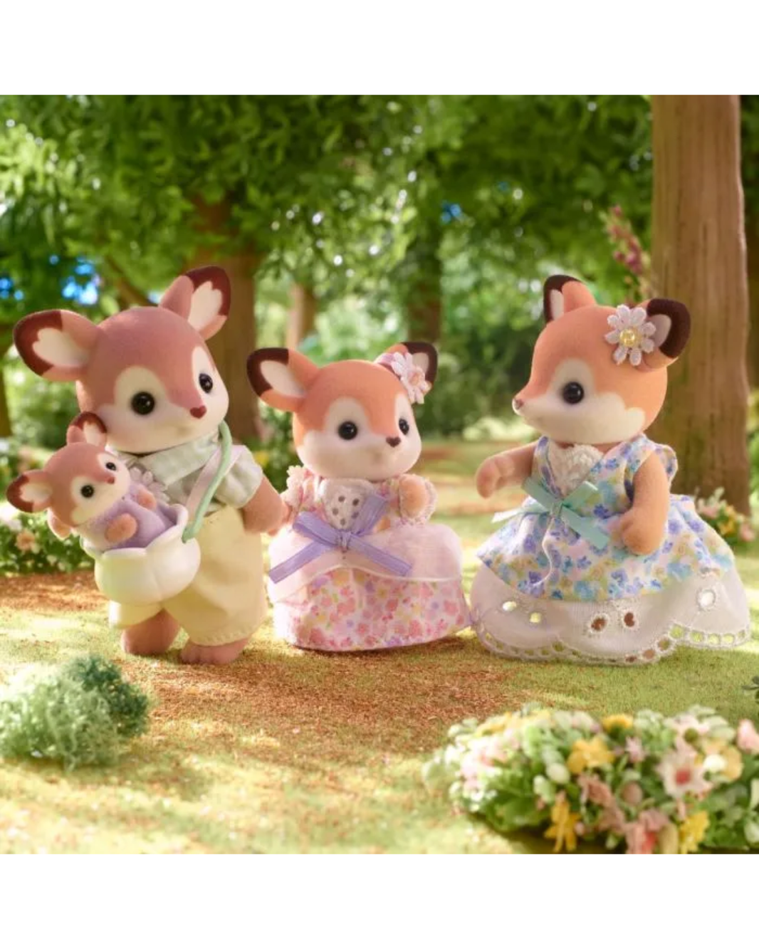 Four sylvanian animal toy figures stand in a sunlit forest setting with trees, grass, and flowers. The figures are dressed in pastel clothing.