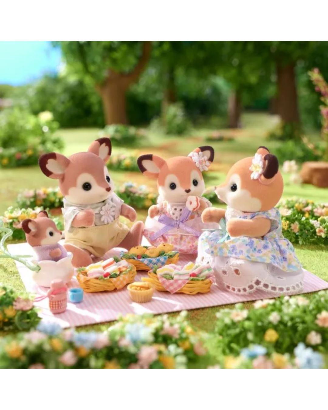 A family of four Sylvanian  Deer figurines posed outdoors on a pink picnic blanket in a lush green garden setting, surrounded by flowers and picnic baskets.