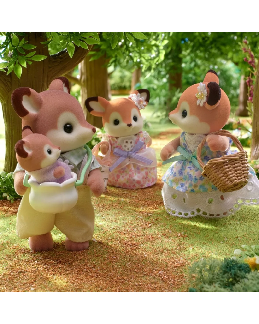 Four sylvanian animal toy figures stand in a sunlit forest setting with trees, grass, and flowers. The figures are dressed in pastel clothing.