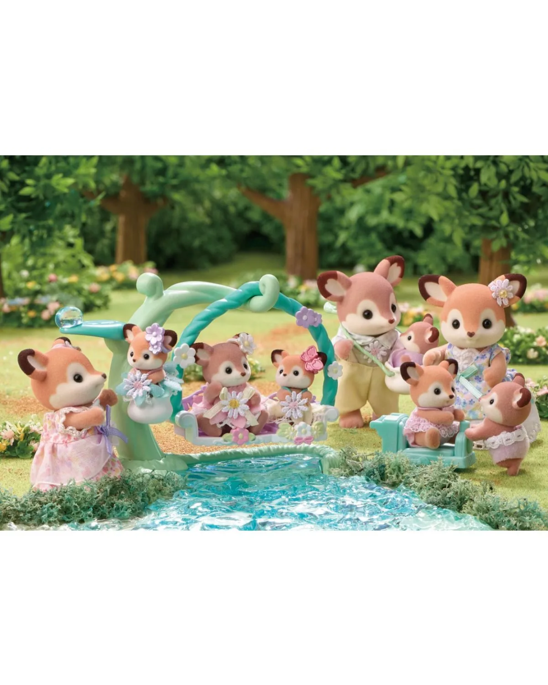 Four sylvanian animal toy figures stand in a sunlit forest setting with trees, grass, and flowers and a lake. The figures are dressed in pastel clothing.