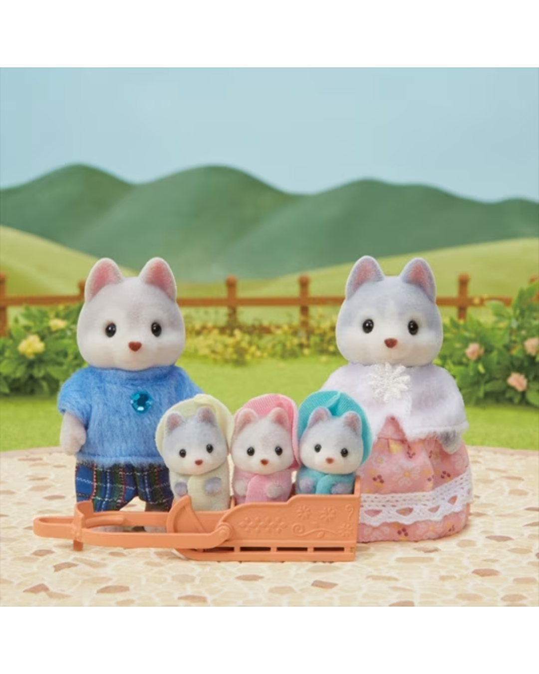 A Sylvanian Family huskey family figurine set featuring a mother in a  dress, a father  in a blue shirt and plaid shorts, and three baby huskies sitting in an orange sled, all set against a stylized green hill background.