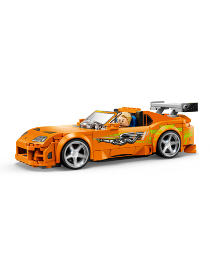 An orange toy sports car built from LEGO, featuring a small minifigure driver, silver wheels, and green and yellow graphic decals, shown against a plain white background.