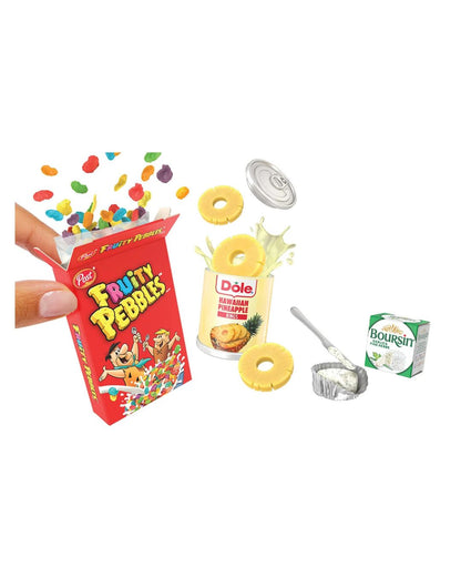 A Miniverse toy set depicting a small red box of Frito-Lay Fruity Pebbles, a can of Dole Hawaiian Punch, a small carton of Boursin, a spoon, and small fruit and candy pieces, shown on a plain white background with a hand holding the toy box.