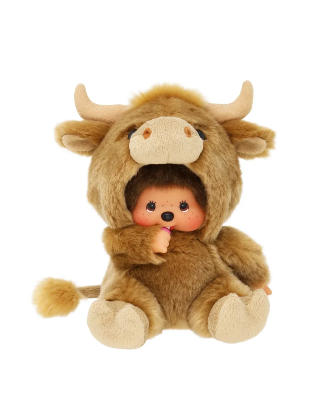 A Monchhichi featuring a brown and beige bull costume hood with horns, enclosing a small doll with dark hair, pink cheeks, and a black nose, isolated on a white background.