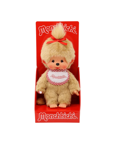 A Monchichi plush toy doll with light brown fur, a red bow, and a red-and-white checkered bib, displayed inside a red retail box with the Monchichi brand name.