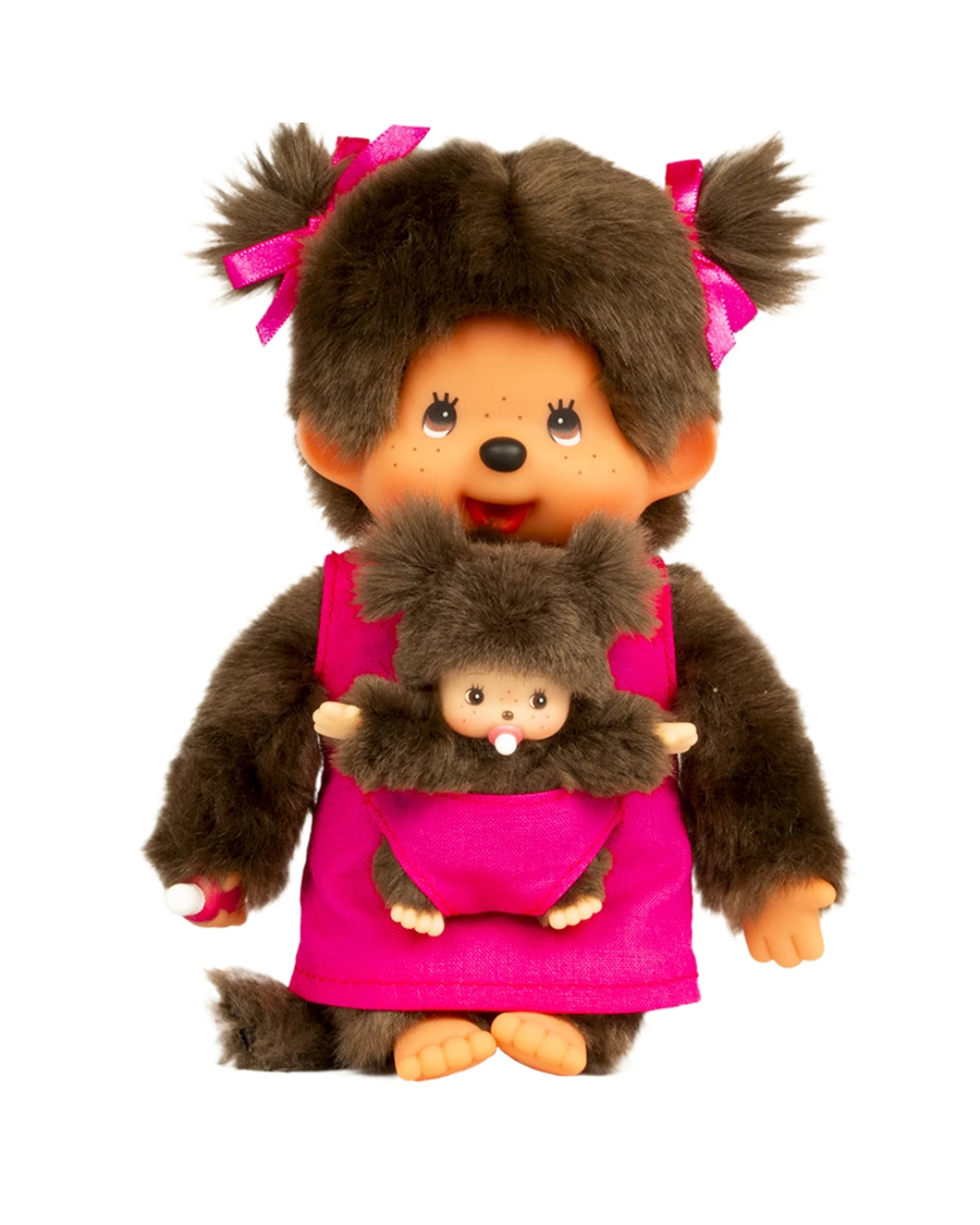 A monchhichi plush with brown faux fur, an orange face, and pink hair bows, wearing a bright pink dress and holding a smaller matching plush character against a plain white background.