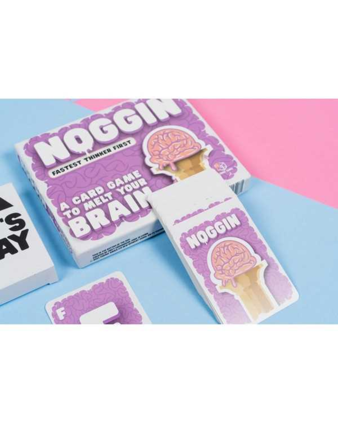 Noggin card game set with a purple and white box, a white card sleeve featuring a pink brain ice cream cone graphic, and a card on a split pink and light blue background.