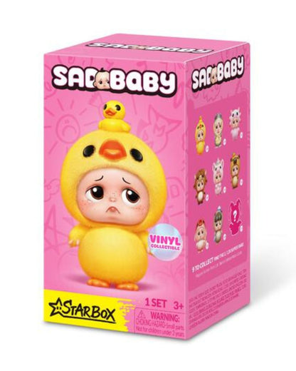A pink Starbaby vinyl mystery figure box featuring a sad yellow duck-cloaked baby character with a small yellow duck on its head, shown on a white background.
