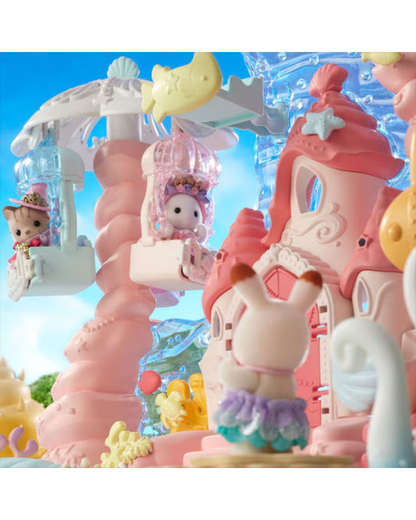 A pastel-colored toy playset featuring a pink castle, a spiral staircase tower, a yellow crescent moon, and small figurines including a rabbit in a tutu and a cat in a carriage, set against a bright blue sky background.