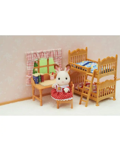 A miniature dollhouse nursery scene with a white rabbit figurine wearing a red polka-dot dress, sitting at a small wooden desk. To the right is a light wood twin and single bed frame with bedding, and a window with pink plaid curtains on the left.