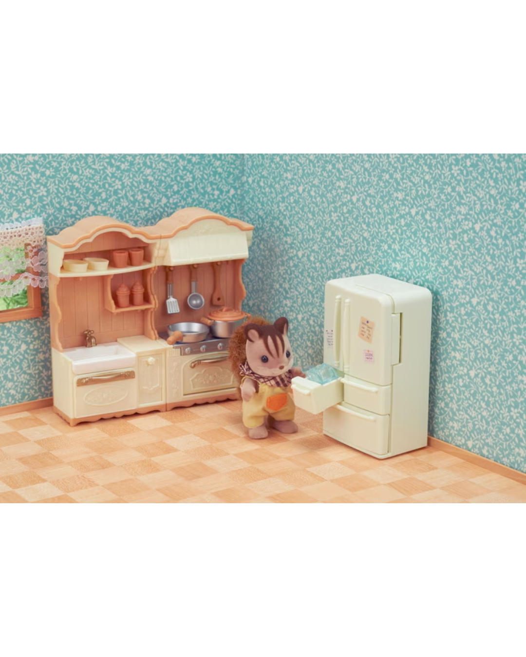A sylvanian figurine stands beside a miniature toy kitchen set and refrigerator in a staged room with patterned blue wallpaper and a checkered floor.