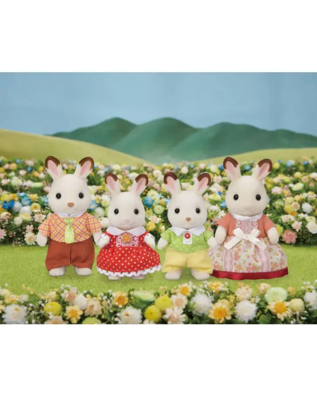 Four Sylvanian Family figurines dressed in colorful outfits, standing in a field of flowers with green hills and a blue sky backdrop.