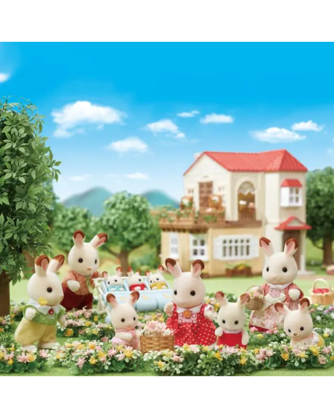 A family of Sylvanian rabbits gathered outdoors in a flowerbed with a small house and trees in the background. The rabbits are dressed in colorful clothing and appear to be playing or having a picnic in a staged garden scene.