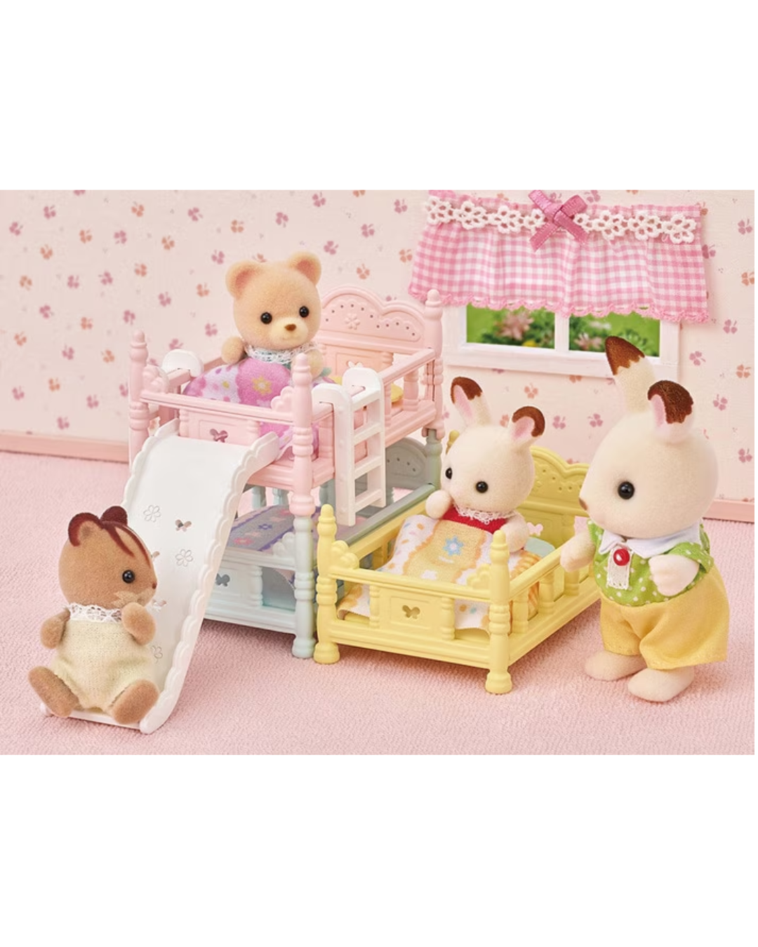 A Sylvanian Families toy set featuring animal characters in a pink bedroom scene with two bunk beds, one in pink and one in yellow, along with a white slide and a window.