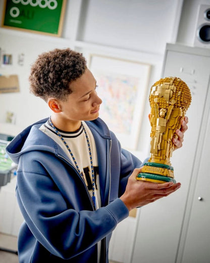 Person holding a large, detailed model of a trophy indoors.