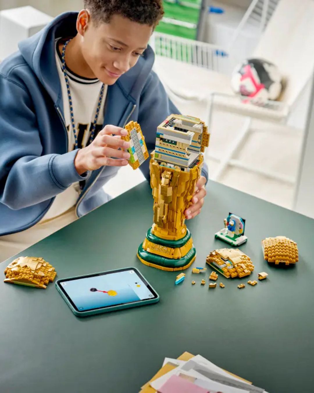 Person building a LEGO set on a table with a tablet nearby