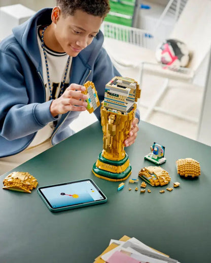 Person building a LEGO set on a table with a tablet nearby
